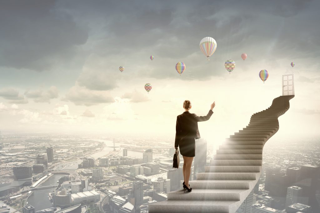 Businesswoman Walking Up Staircase To Door In Sky